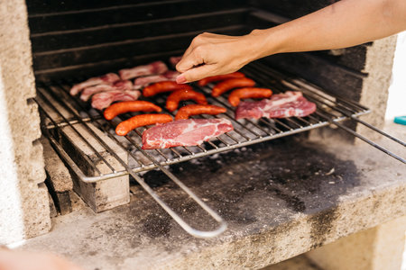 hands of young latin woman rubbing salt on meat at a barbecueの写真素材