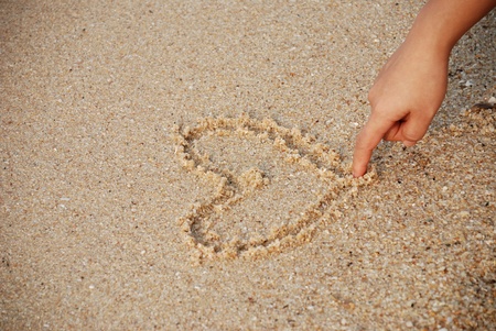 heart drawing on the sand with nice lady handの写真素材