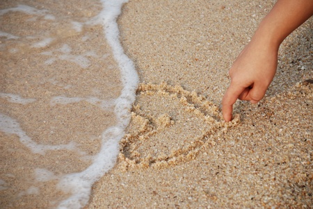 heart drawing on the sand with nice lady handの写真素材