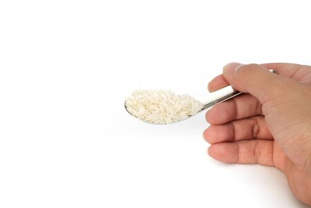 holding raw rice in spoon isolated on white backgroundの写真素材