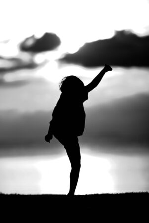 Silhouette of a boy  on sunset background in black and white.の写真素材