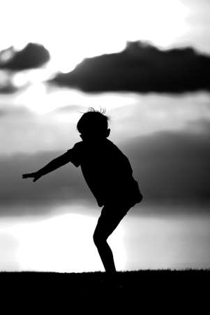 Silhouette of a boy  on sunset background in black and white.の写真素材