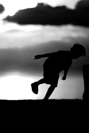 Silhouette of a boy  on sunset background in black and white.の写真素材