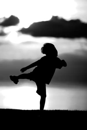 Silhouette of a boy  on sunset background in black and white.の写真素材