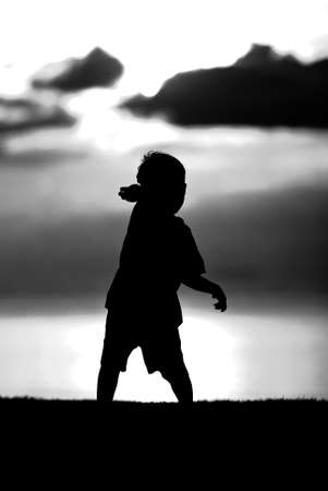 Silhouette of a boy  on sunset background in black and white.の写真素材