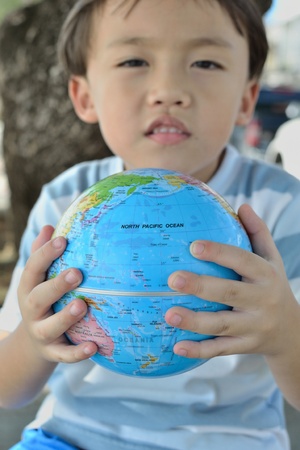 cute asian boy portrait with blue globe in two hands.の写真素材