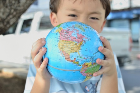 cute asian boy portrait with blue globe in two hands.の写真素材