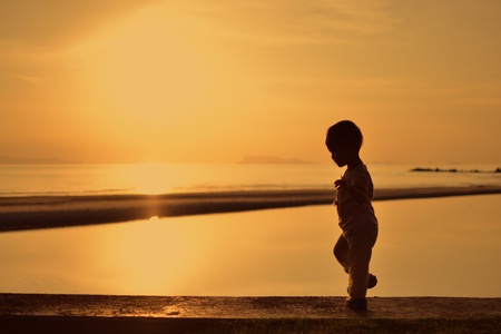 silhouette of small girl  during sunset with ocean background.の写真素材