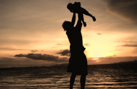 silhouette of daddy and small girl on the beach at dusk.の写真素材