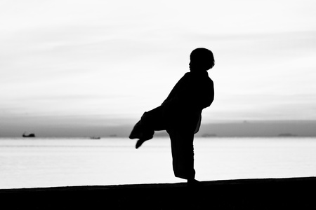 Silhouette taekwondo boy on the beach at dusk. Black and whit picture.の写真素材