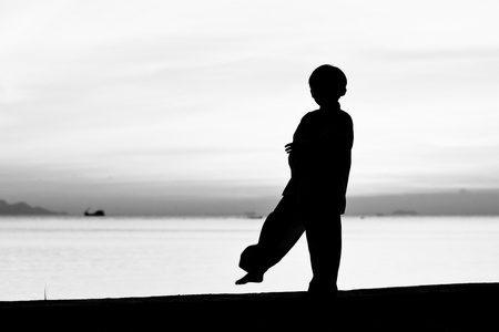 Silhouette taekwondo boy on the beach at dusk. Black and whit picture.の写真素材