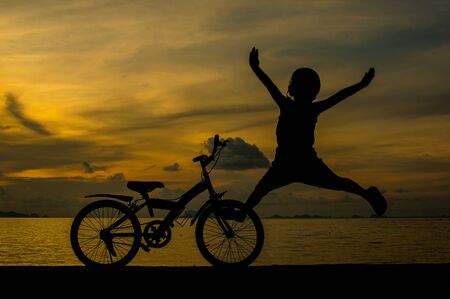 silhouette of small boy on bike at dusk.の写真素材