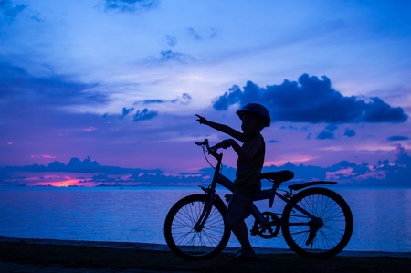 silhouette of small boy on bike at dusk.の写真素材