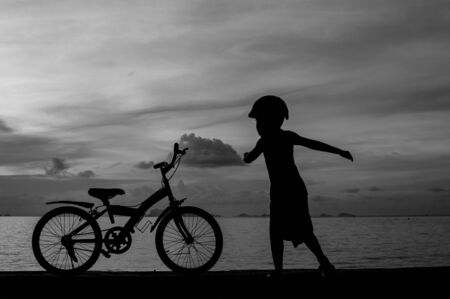 silhouette of small boy on bike at dusk.の写真素材