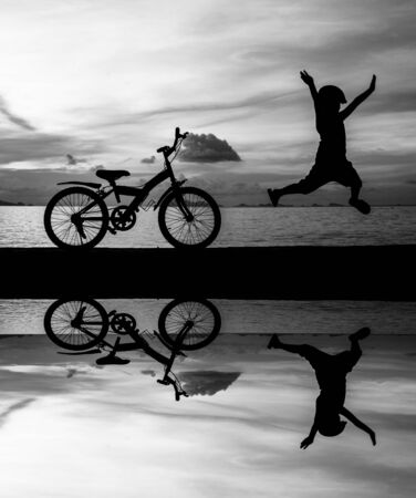 silhouette of small boy on bike at dusk.の写真素材