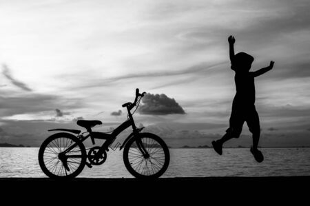 silhouette of small boy on bike at dusk.の写真素材