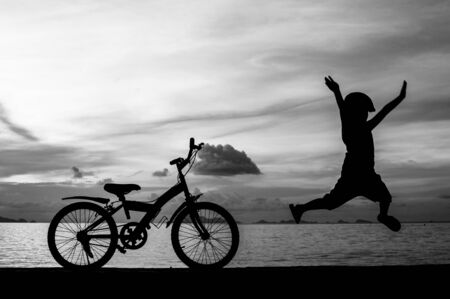 silhouette of small boy on bike at dusk.の写真素材