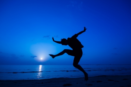silhouette of happy man jumping at the beach.の写真素材