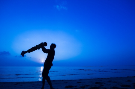 silhouette of happy man playing with daughter at the beach.の写真素材