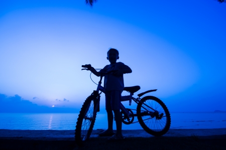 silhouette of small boy with bycycle at the beach.の写真素材