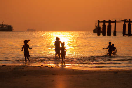 silhouette of people activity on the beach at sunset.の写真素材