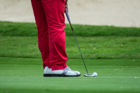 Male golfer putting a golf ball in to hole.の写真素材