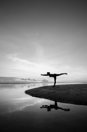 Silhouette woman with yoga posure on the beach at sunset with reflection.の写真素材
