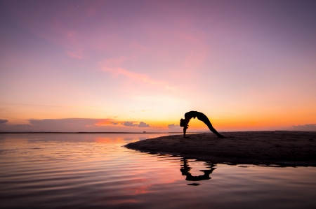 Silhouette woman with yoga posure on the beach at sunset with reflection.の写真素材