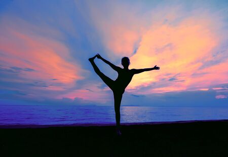 Silhouette one woman with professional yoga posture on the beach at sunset.の写真素材