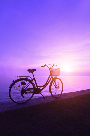 Silhouette of a bicycle on the beach at dusk.の写真素材