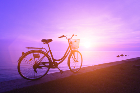 Silhouette of a bicycle on the beach at dusk.の写真素材