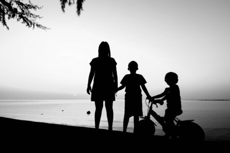 Silhouette of family on the beach at dusk.の写真素材