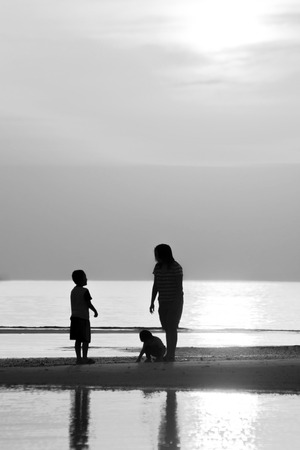Silhouette of family on the beach during sunset.の写真素材