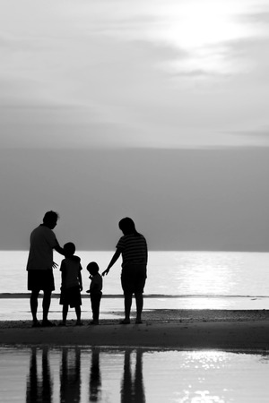 Silhouette of family on the beach during sunset.の写真素材
