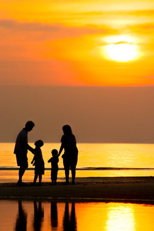 Silhouette of family on the beach during sunset.の写真素材