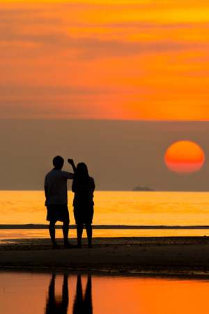 Silhouette of family on the beach during sunset.の写真素材