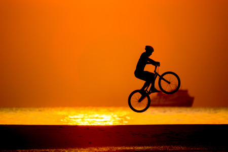 bmx rider action against sunset on the beach.の写真素材