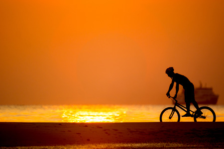 bmx rider action against sunset on the beach.の写真素材