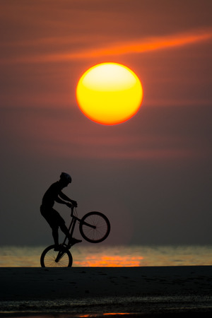 bmx rider action against sunset on the beach.の写真素材