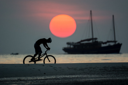 bmx rider action against sunset on the beach.の写真素材