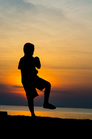 Silhouette of a boy on the beach during sunset.の写真素材
