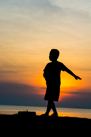 Silhouette of a boy on the beach during sunset.の写真素材