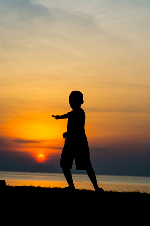 Silhouette of a boy on the beach during sunset.の写真素材