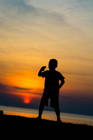 Silhouette of a boy on the beach during sunset.の写真素材