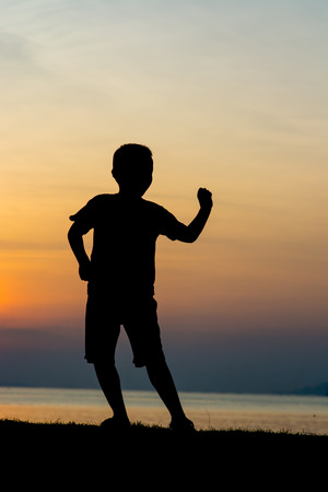 Silhouette of a boy on the beach during sunset.の写真素材