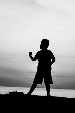 Silhouette of a boy on the beach during sunset.の写真素材