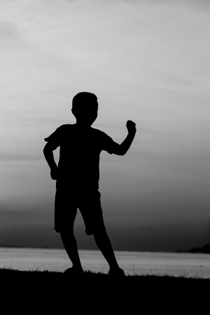 Silhouette of a boy on the beach during sunset.の写真素材