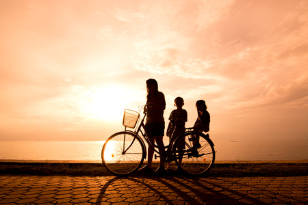 Biker family silhouette , family at the beach at sunset.の写真素材
