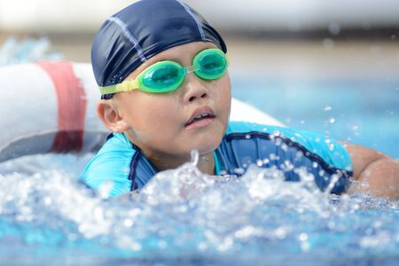 Small asian kid in swimming suit at the pool.の写真素材