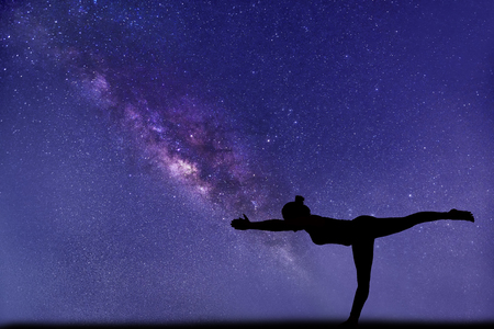 milky way, close up view. Professional woman yoga pose foreground.の写真素材